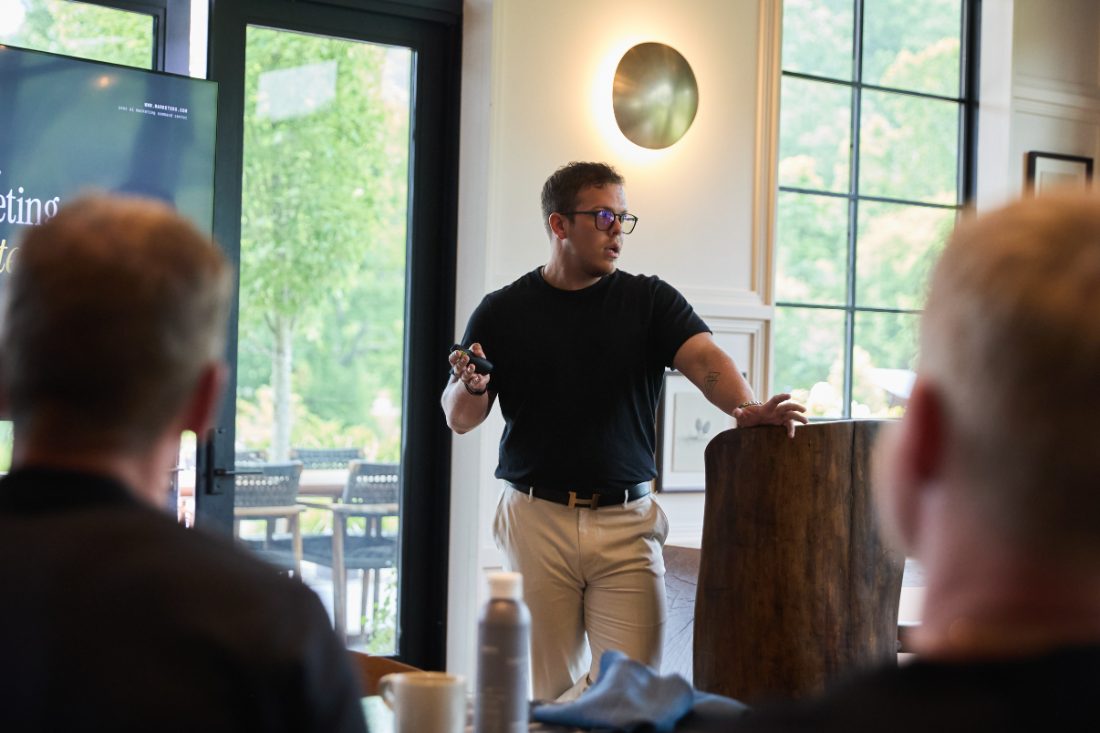 Ashton Shanks, founder of Hemon, presenting to a small seated group in a daylit room.
